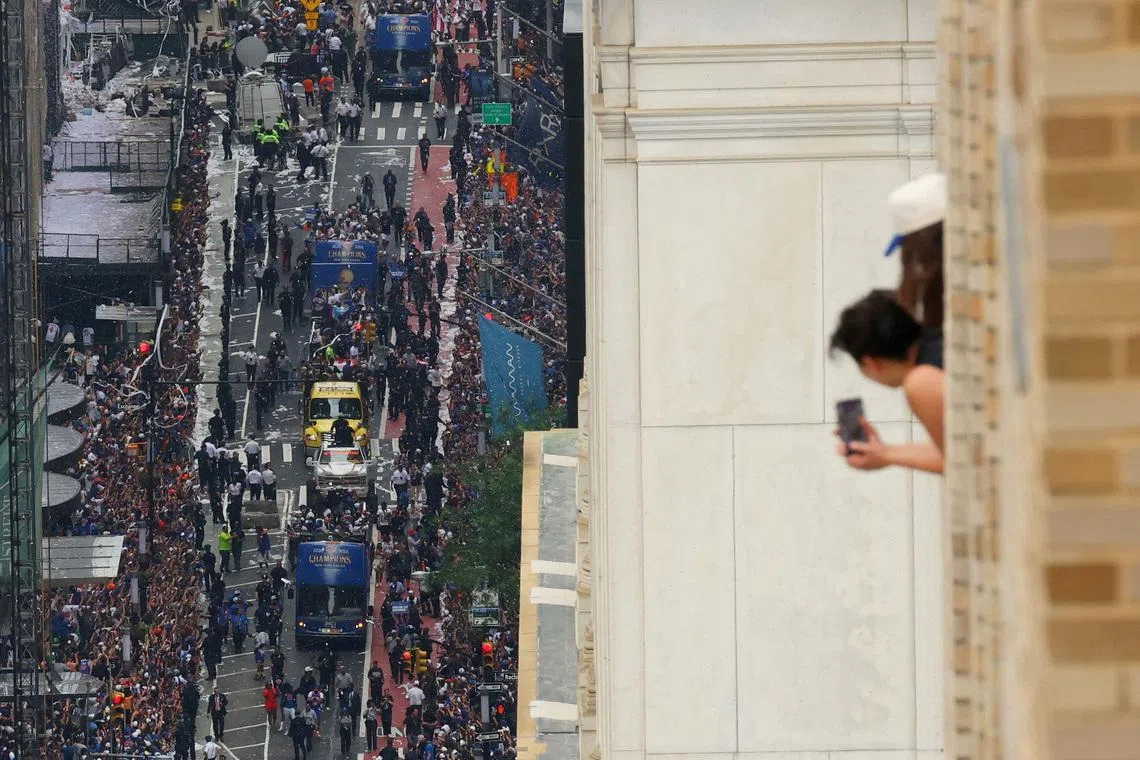 New York Knicks fans celebrating from balconies as the players travel along broadway, during their victory parade celebrating the NBA Finals win, in New York City, on June 18, 2026.