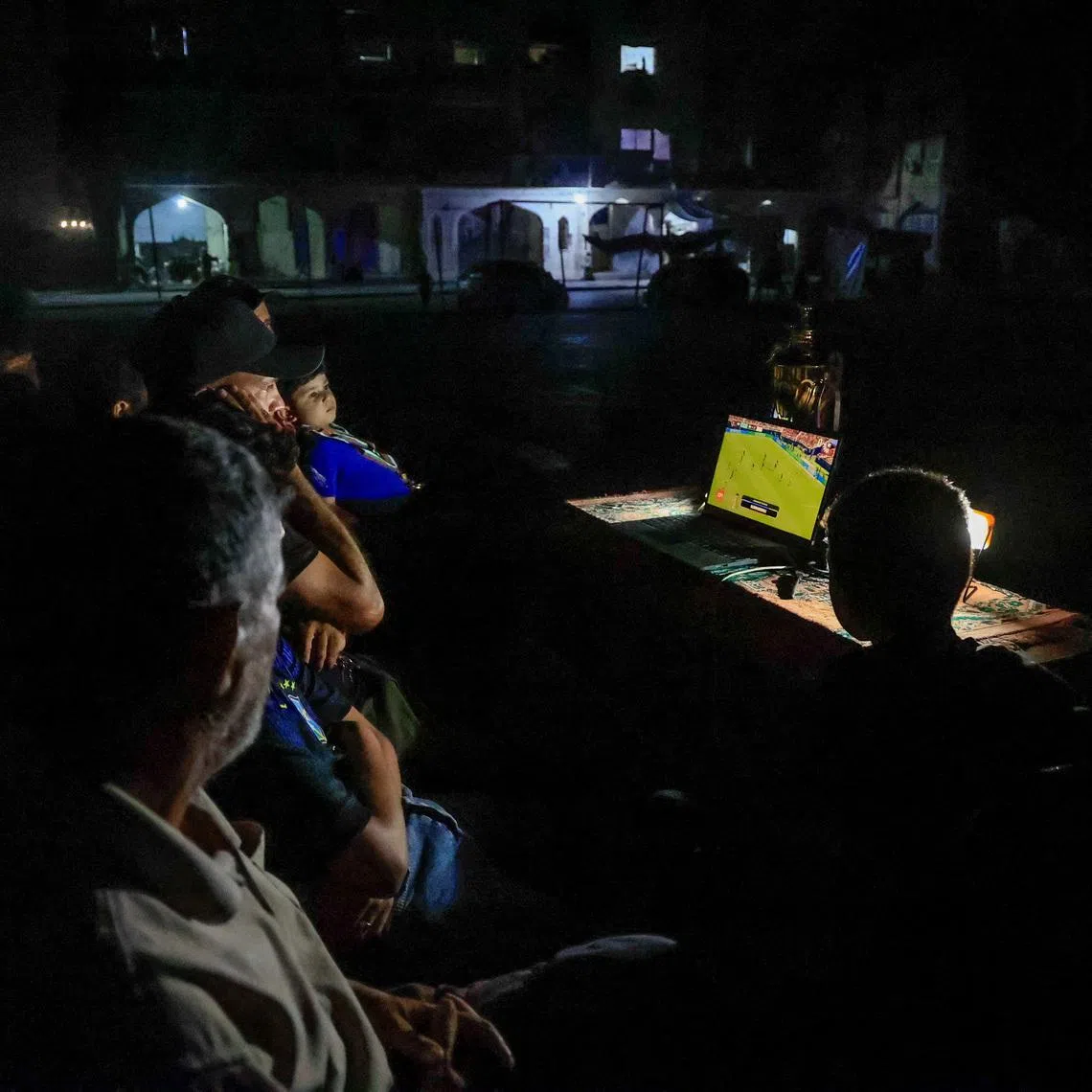 Former Palestinian soccer player Fadi Al-Arawi watches a World Cup match streamed on a laptop alongside others in theGaza Strip on June 13.