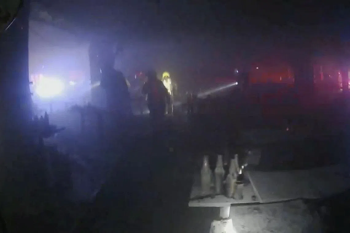 Rescue workers use flashlights as they inspect the site of a deadly fire at a pub in Bangkok, Thailand, on July 13.
