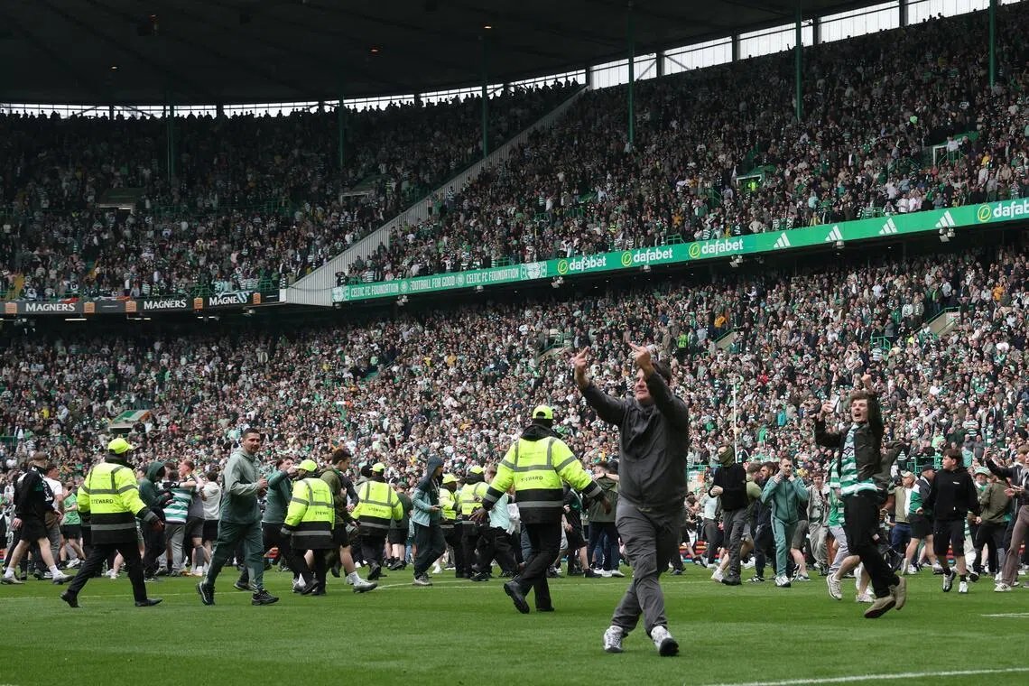 Celtic fans invade the pitch after Callum Osmand scores their third goal in the 3-1 win over Heart of Midlothian to secure the Scottish Premiership at Celtic Park in Glasgow on May 16, 2026.
