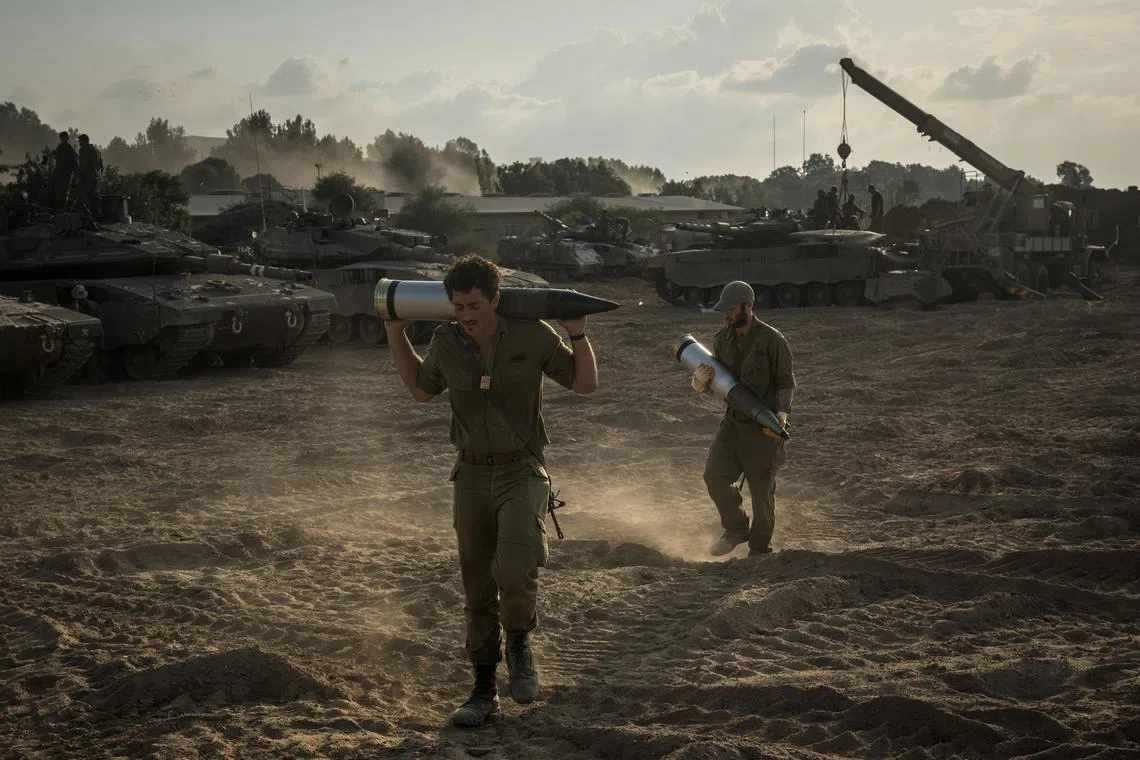 Israeli soldiers load tank shells as their unit masses in Be'eri, near the border with the Gaza Strip.