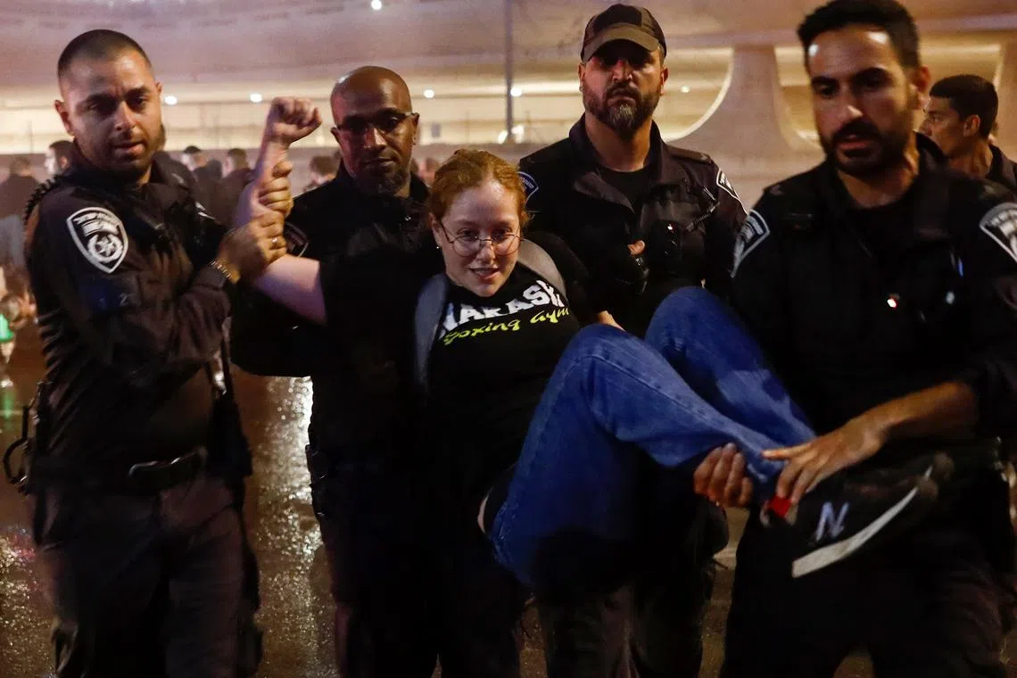 Police remove a protester blocking a highway in Tel Aviv.