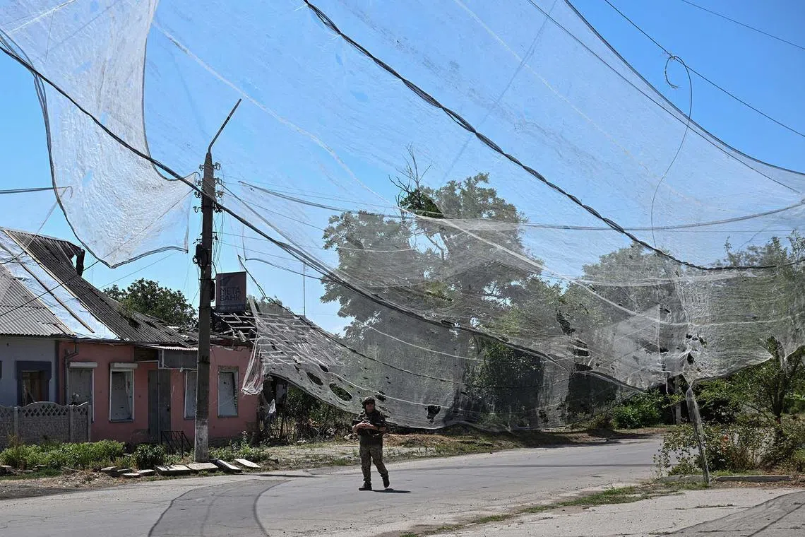 A Ukrainian service member walking on a street protected with anti-drone nets, amid Russia's attack on Ukraine, in the frontline town Orikhiv in Zaporizhzhia region, Ukraine, July 23, 2025. 