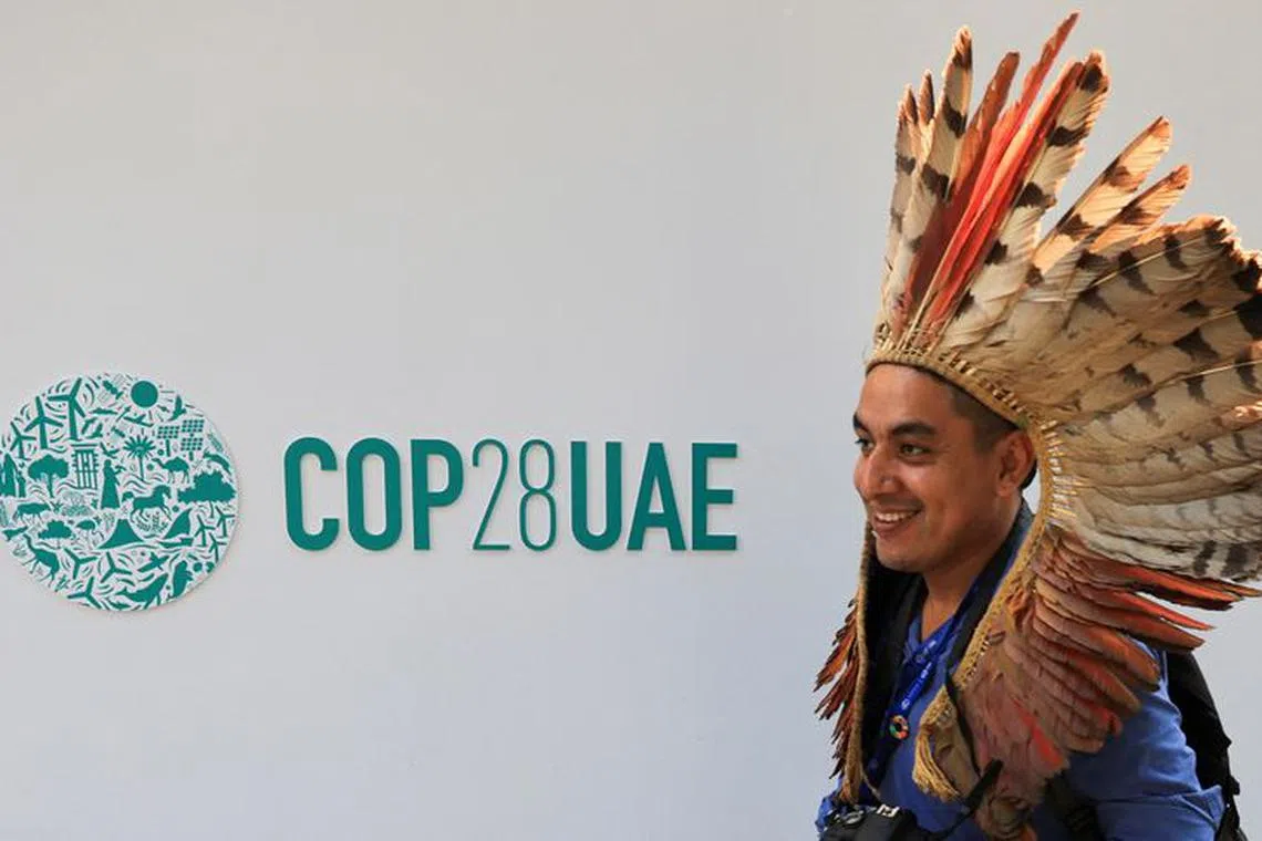 A delegate walks past a logo of the COP28 climate summit in Dubai, United Arab Emirates, December10, 2023. REUTERS/Thaier Al Sudani