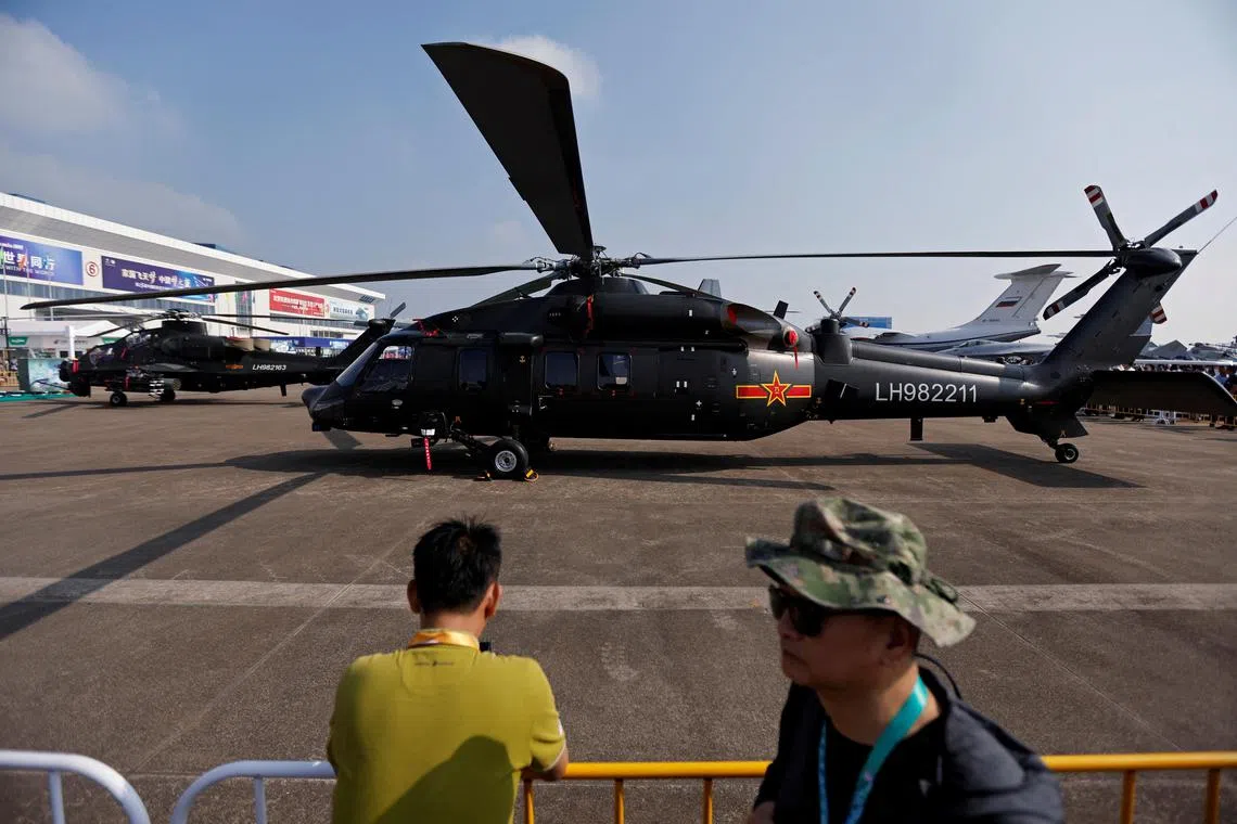 People stand near a Z-20 helicopter displayed at the China International Aviation and Aerospace Exhibition in Zhuhai, China.