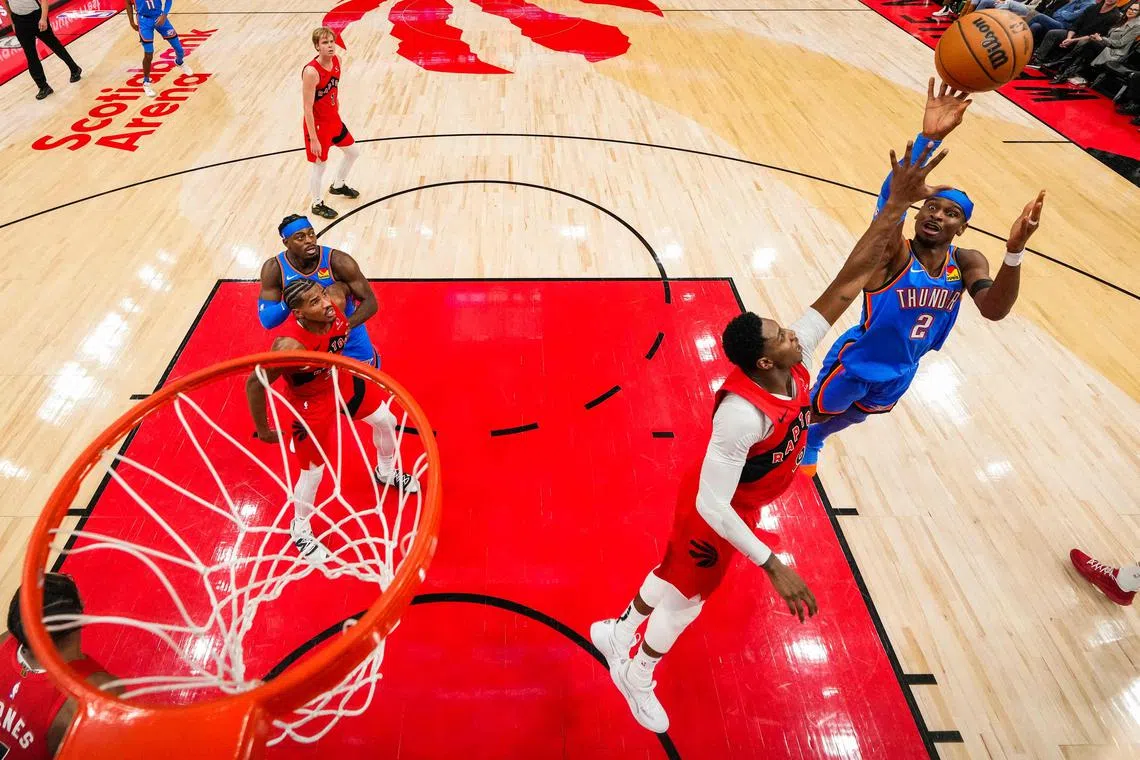 Shai Gilgeous-Alexander of the Oklahoma City Thunder shoots the ball against RJ Barrett of the Toronto Raptors at Scotiabank Arena.