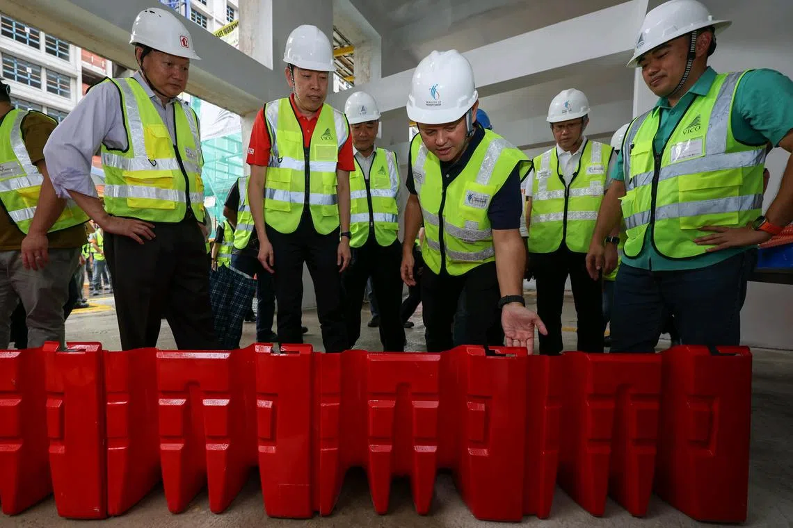 Senior Minister of State for Manpower Zaqy Mohamad (centre) taking a look at the flood barrier during the launch of the Workplace Safety and Health  guidelines on preparing for adverse weather, at the Central Weave @ AMK site in Ang Mo Kio on April 4, 2025.