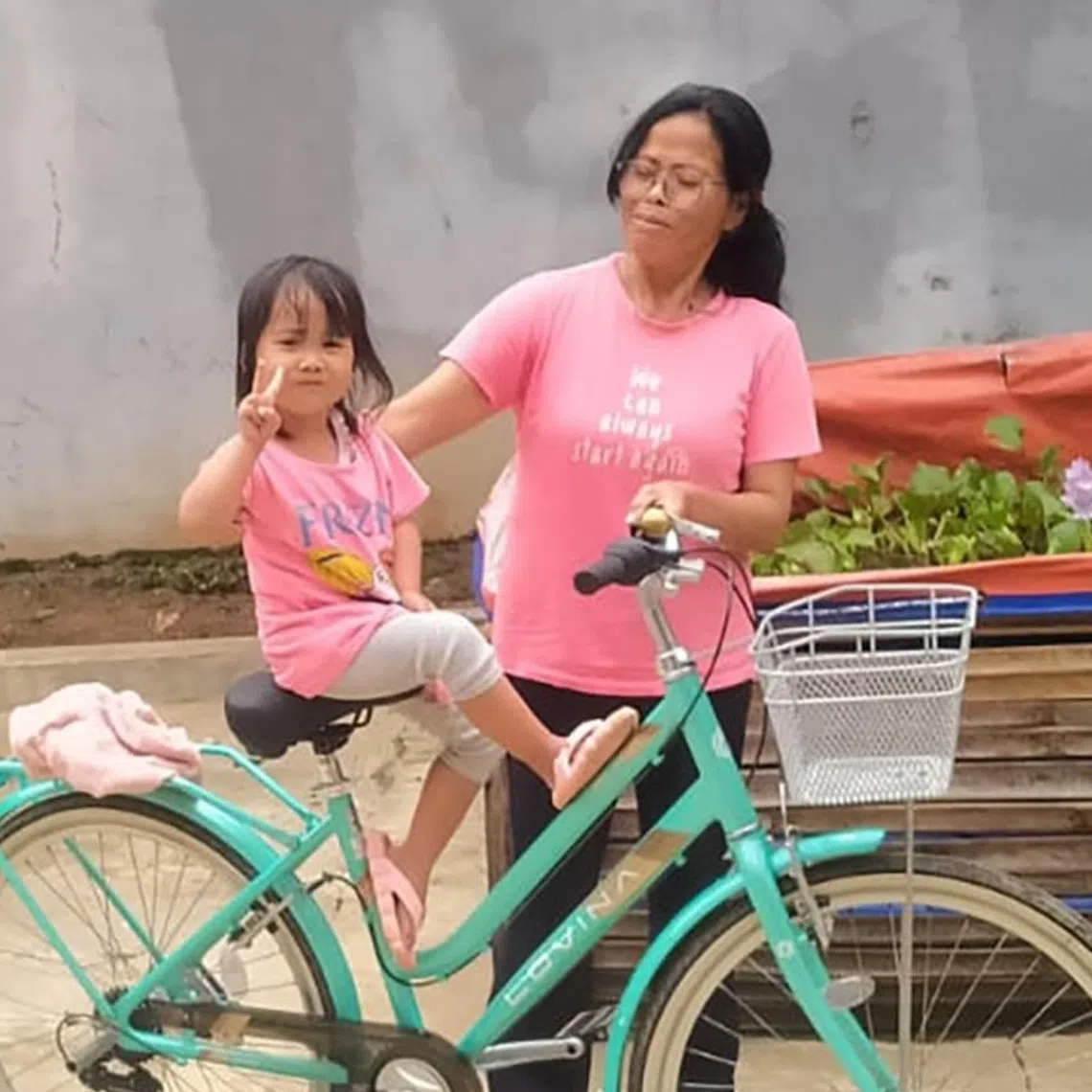 Ms Darwati with her four-year-old granddaughter posing in matching pink T-shirts outside their house in Majenang district, Cilacap regency, Indonesia.