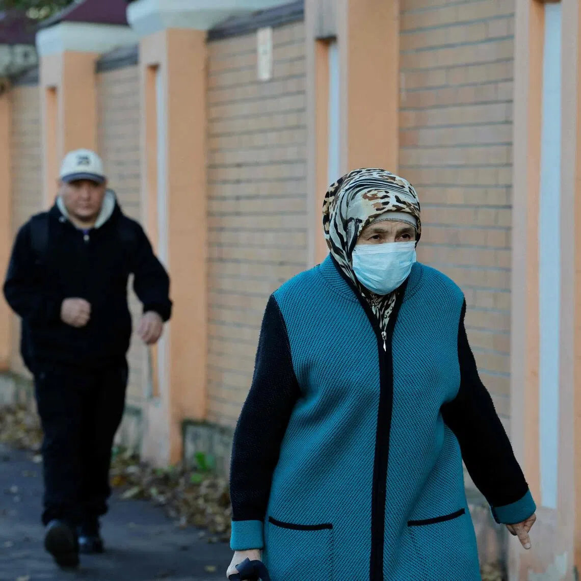 A masked woman walking past the Irkutsk Anti-Plague Research Institute, in the Russian city of Irkutsk, on Oct 7.