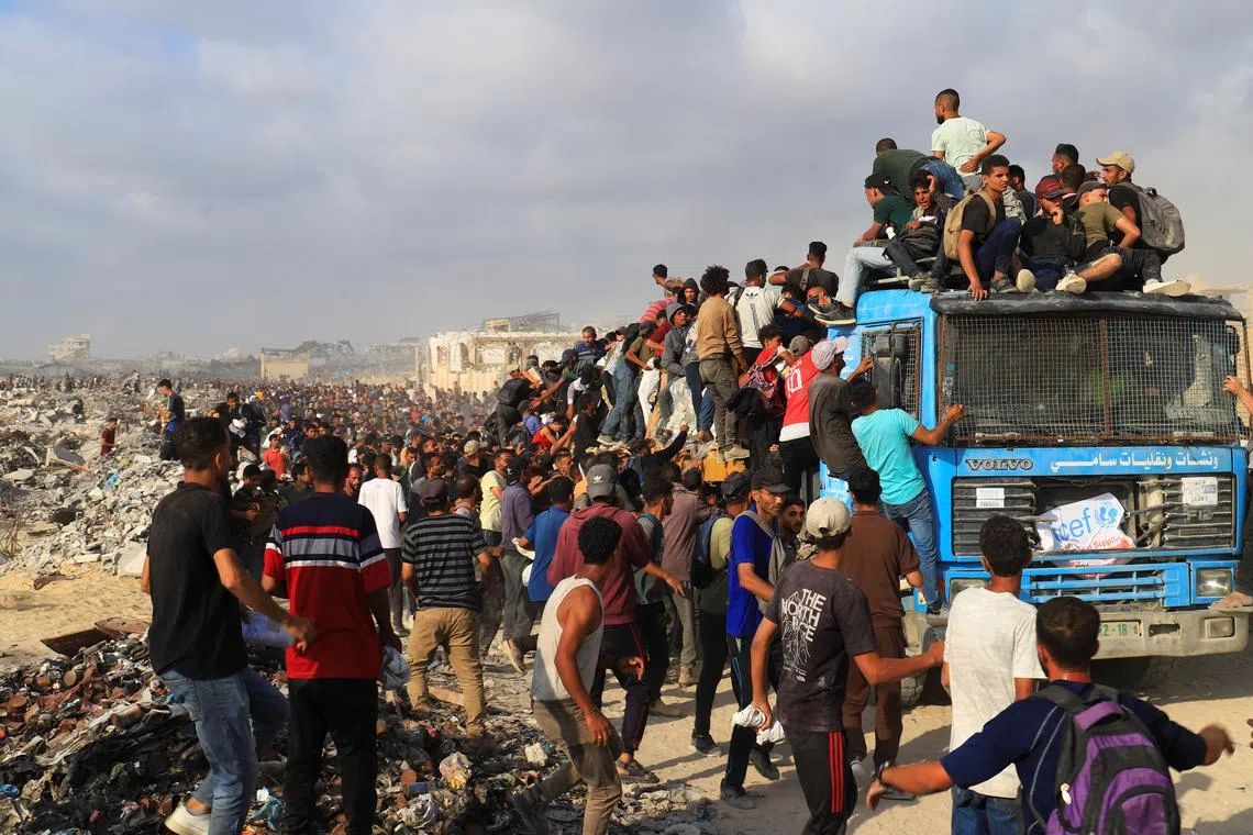 Palestinians climb a vehicle as they gather to receive aid supplies in Beit Lahia, in the northern Gaza Strip, on June 23.