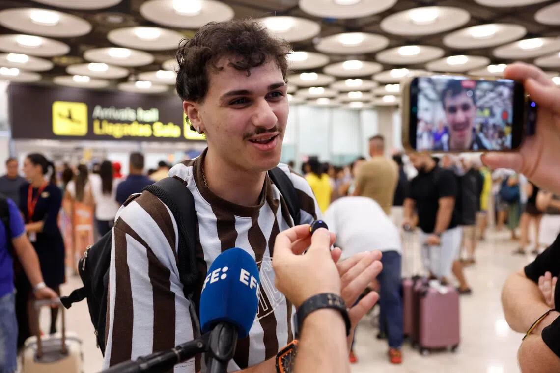 A young man speaking into a microphone in a large indoor area.