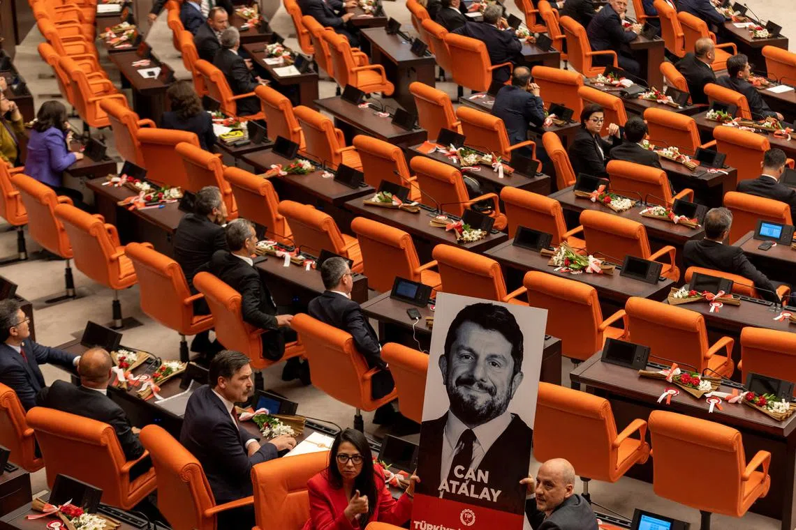 Erkan Bas, the leader of Workers' Party of Turkey (TIP) and his party MPs Sera Kadigil and Ahmet Sik display a portrait of Can Atalay, a jailed MP of TIP, during a swearing-in ceremony at the Turkish parliament in Ankara, Turkey, June 2, 2023. Atalay has not been released despite a law that opens a way for jailed politicians to be released from prison if they are elected to parliament. REUTERS/Umit Bektas/File Photo