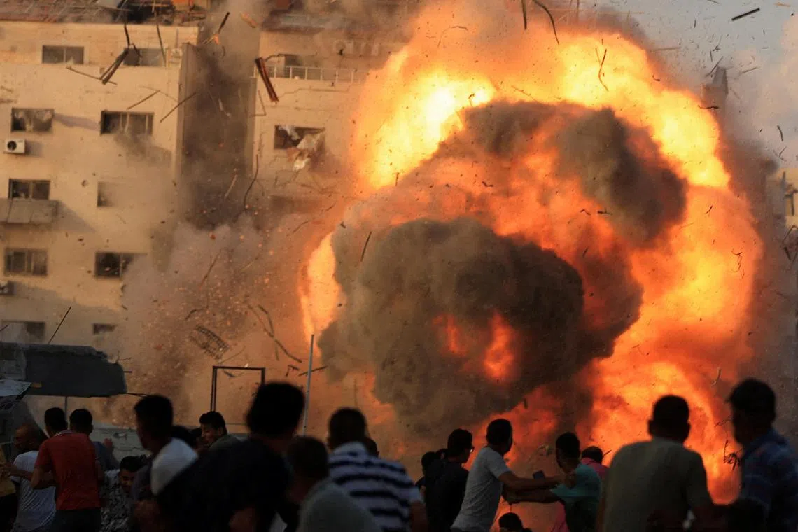 Palestinians watching as a residential building collapses after an Israeli air strike, in Gaza City, on Sept 7. 