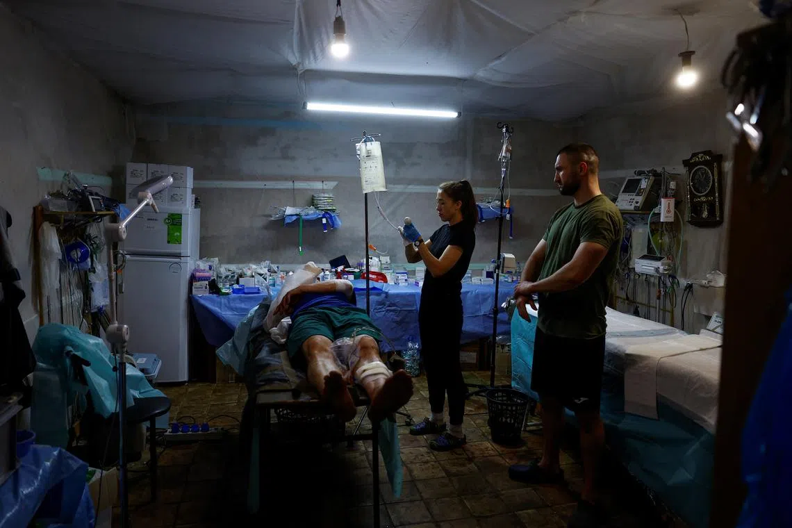 Medics speak with injured Ukrainian serviceman Vitalii after treating him at a stabilisation point, amid Russia's attack on Ukraine, near a front line in Kharkiv Region, Ukraine June 2, 2024. REUTERS/Valentyn Ogirenko