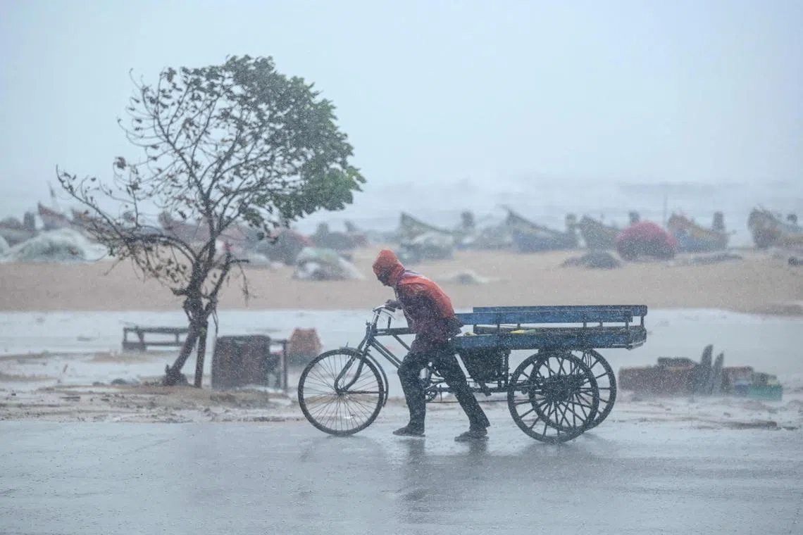 TOPSHOT - A man pulls his three-wheeler cart amid heavy wind and rainfall at the Marina Beach in Chennai on November 30, 2024, ahead of the landfall of cyclone Fengal in India's state of Tamil Nadu. Cyclonic storm Fengal is forecast to make landfall in Tamil Nadu state with sustained winds of 70-80 kilometres an hour (43-50 mph) in the afternoon, India's weather bureau said. (Photo by R.Satish BABU / AFP)