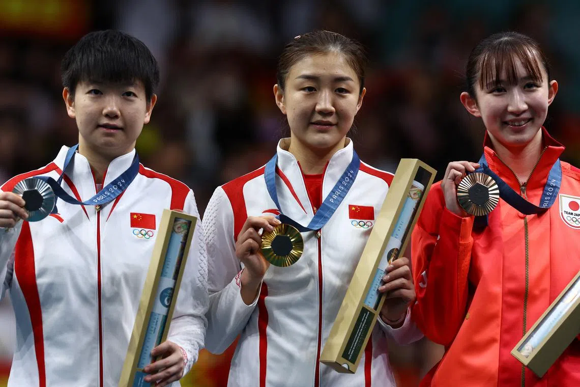 Paris 2024 Olympics - Table Tennis - Women's Singles Victory Ceremony - South Paris Arena 4, Paris, France - August 03, 2024. Silver medallist Yingsha Sun of China, gold medallist Meng Chen of China and bronze medallist Hina Hayata of Japan celebrate on the podium. REUTERS/Stephanie Lecocq