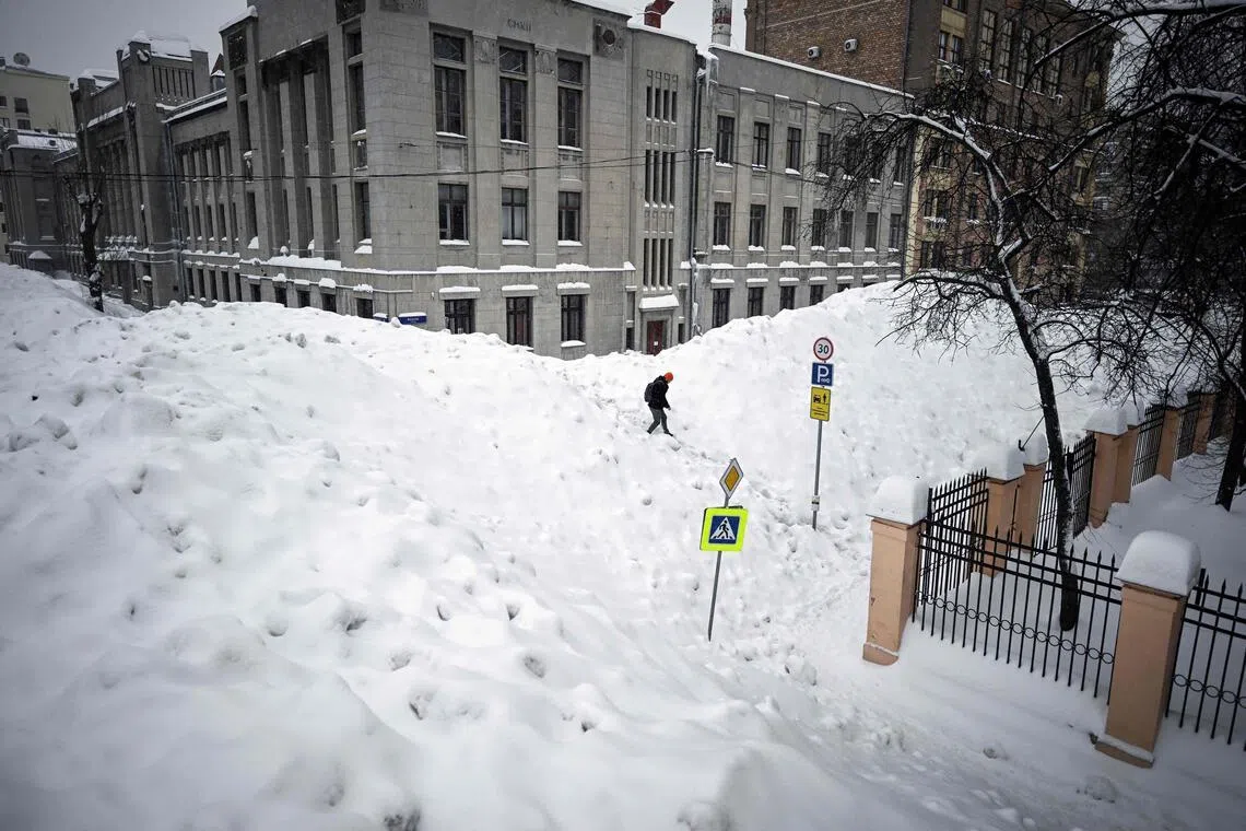 A pedestrian crossing a street that is being used for temporary snow storage in central Moscow on Jan 29.