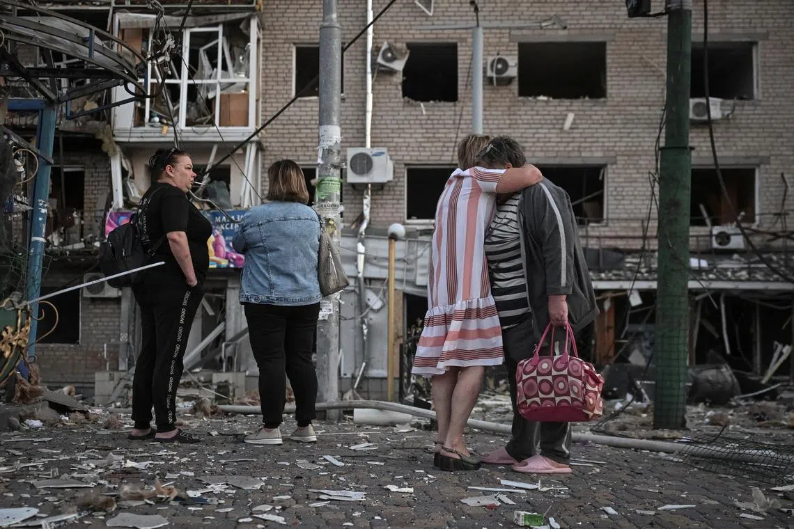 Residents stand at the site of an apartment building hit during a Russian drone and missile strike in Zaporizhzhia, Ukraine on Aug 30.