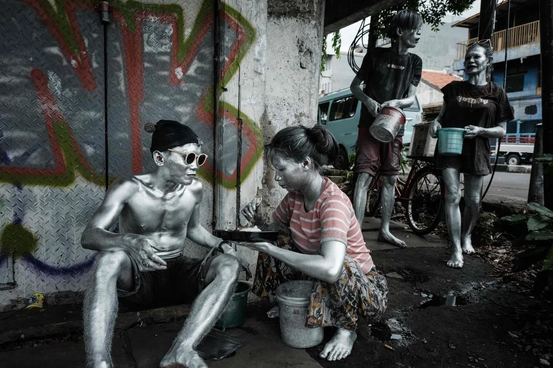 Street performers covered in silver paint taking a break to eat in Jakarta on Feb 23, 2025.