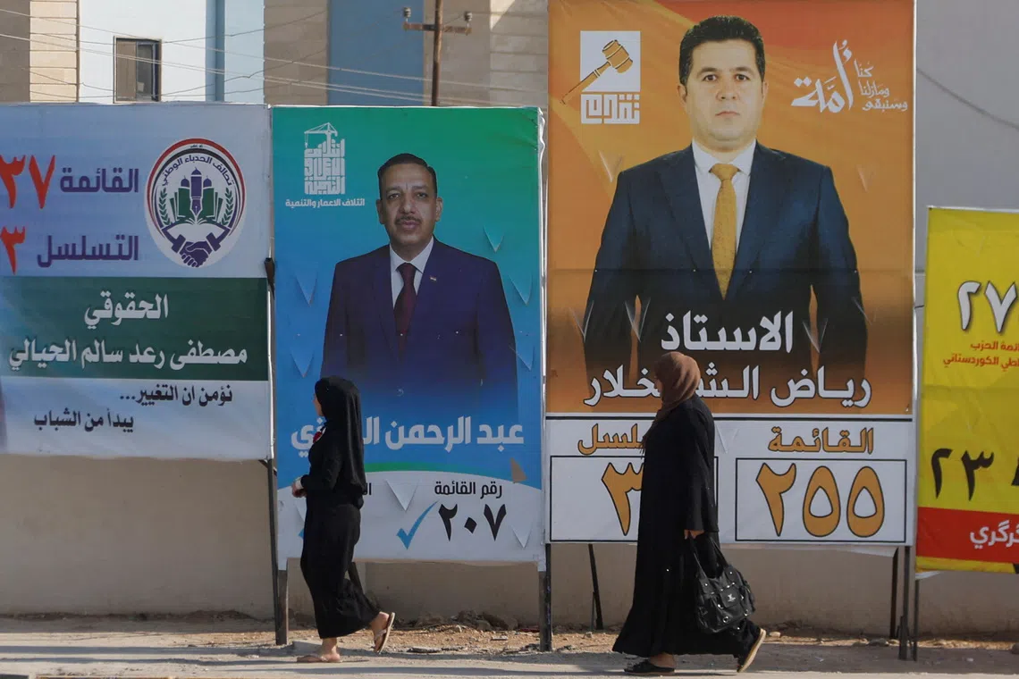 Women walk past campaign posters of candidates ahead of Iraq’s upcoming parliamentary elections in Mosul, Iraq, November 6, 2025. REUTERS/Khalid al-Mousily