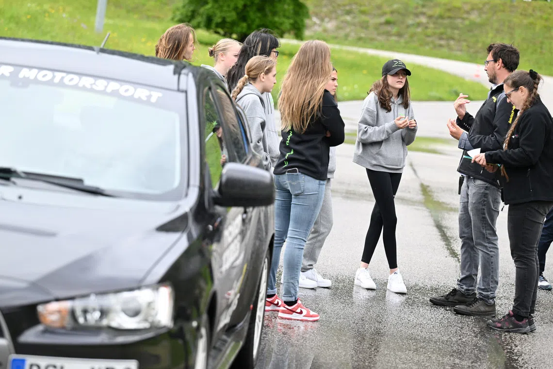 Participants from the More Than Equal Global Driver Development programme with a coach at the training racetrack in Saalfelden, Austria in 2024.