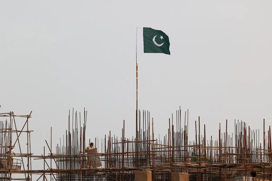 A Pakistani flag flutters over iron scaffoldings as a labourer works at a construction site on the eve of Pakistan's Independence Day celebrations, in Lahore, Pakistan August 13, 2025. REUTERS/Akhtar Soomro/File Photo