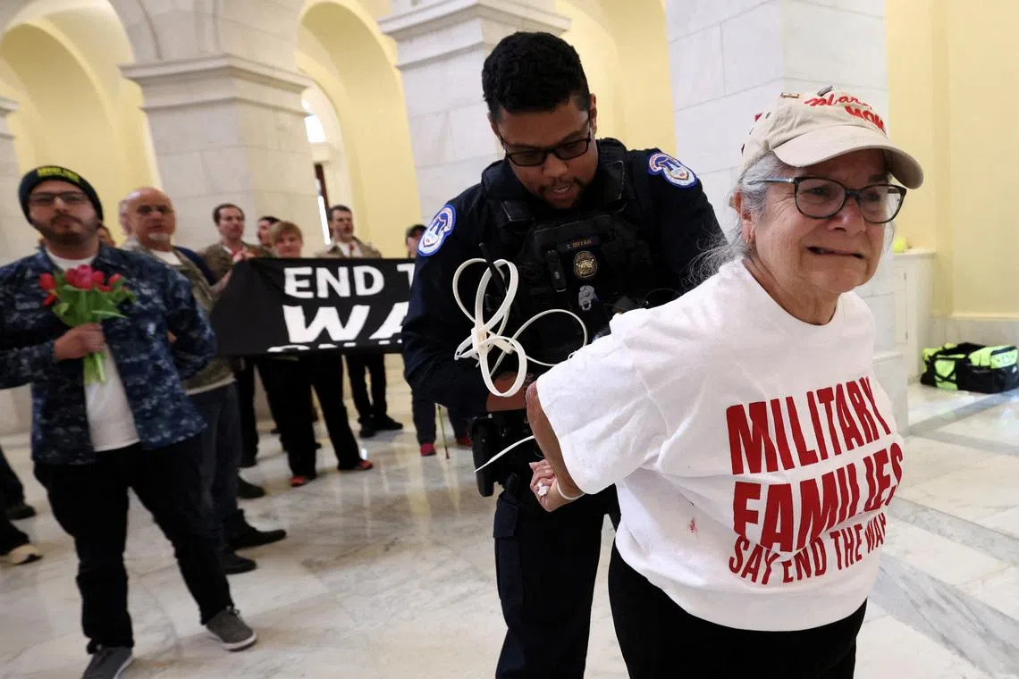 A protester's hands are zip-tied during a protest against the Iran war by veterans from the group, About Face, and members of military families, in the Cannon House Office Building Rotunda on Capitol Hill in Washington, DC, US, on April 20, 2026. 
