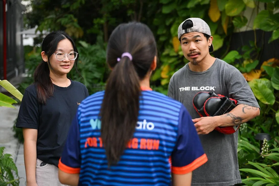 Kelly (not her real name), with Ng Shu Yi (left), a youth advocate from Impart, and Allan Ng, her muay thai coach.