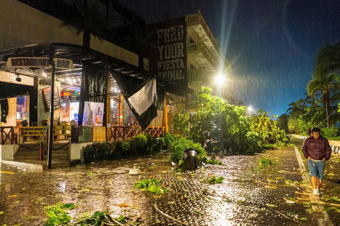 People walk by a restaurant damaged in the aftermath of Hurricane Lidia, in Puerto Vallarta, Mexico October 10, 2023. REUTERS/Christian Ruano