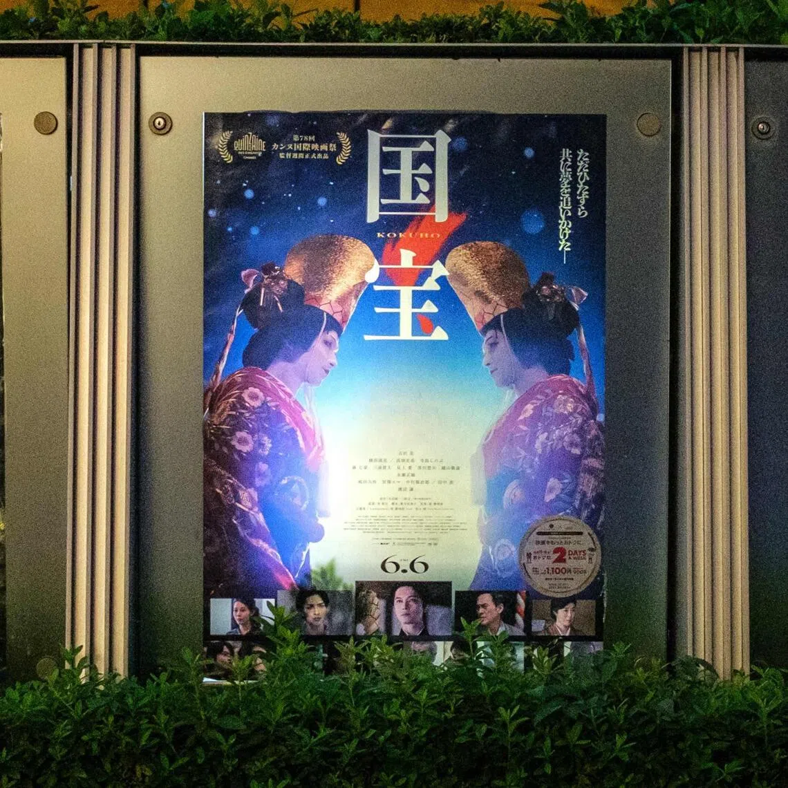 A woman walks past the poster of Japanese movie "Kokuho" (R) outside a cinema in Tokyo's Roppongi district.