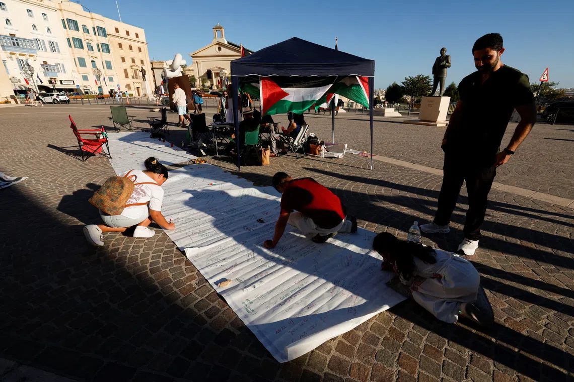 People write messages of support on a banner as activists hold a two-day protest vigil in solidarity with the victims in Gaza outside the Auberge de Castille, the office of Malta's Prime Minister Robert Abela after he announced that Malta will formally recognise the state of Palestine in the coming days, amid the ongoing conflict between Israel and Hamas, in Valletta, Malta, September 21, 2025. REUTERS/Darrin Zammit Lupi/File Photo