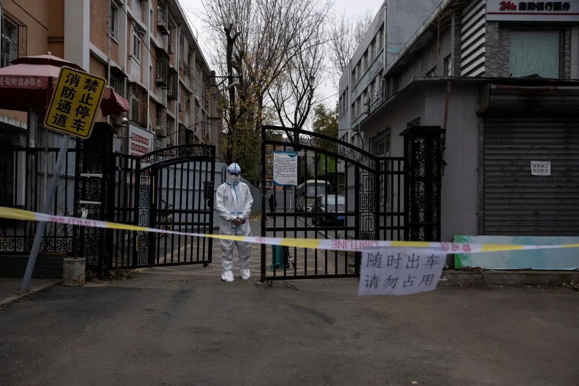 FILE PHOTO: An epidemic-prevention worker in a protective suit stands guard at the gate of a residential compound as coronavirus disease (COVID-19) outbreaks continue in Beijing, China November 28, 2022. REUTERS/Thomas Peter/File Photo
