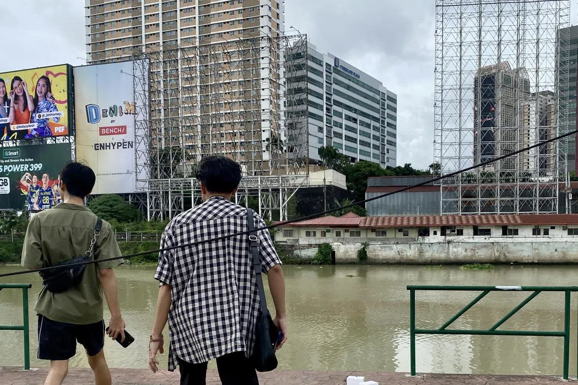 Filipinos walks along advertisements taken down from billboards in preparation for Typhoon Doksuri in Makati city, Metro Manila.