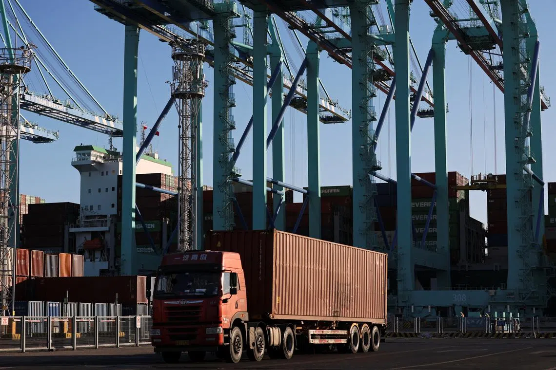 FILE PHOTO: A truck transports a container near gantry cranes unloading containers from a cargo ship, at a port in Tianjin, China February 8, 2025. REUTERS/Florence Lo/File Photo