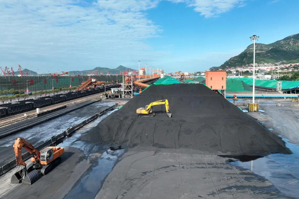 This photo taken on May 24, 2023 shows excavators transferring coal at a port in Lianyungang, in China's eastern Jiangsu province. (Photo by AFP) / China OUT