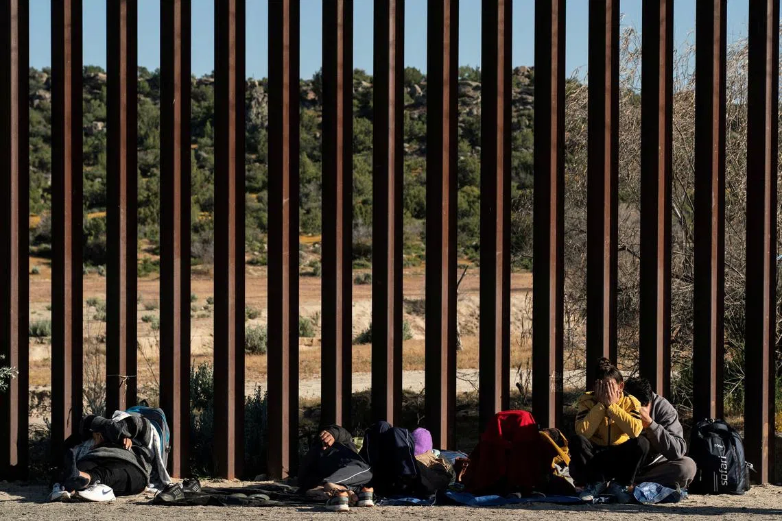 FILE PHOTO: Asylum-seeking migrants from India wait by the border wall while waiting to be picked up by the U.S. Border Patrol after crossing the border from Mexico into the U.S. in Jacumba Hot Springs, California, U.S. April 27, 2024.  REUTERS/Go Nakamura/File Photo