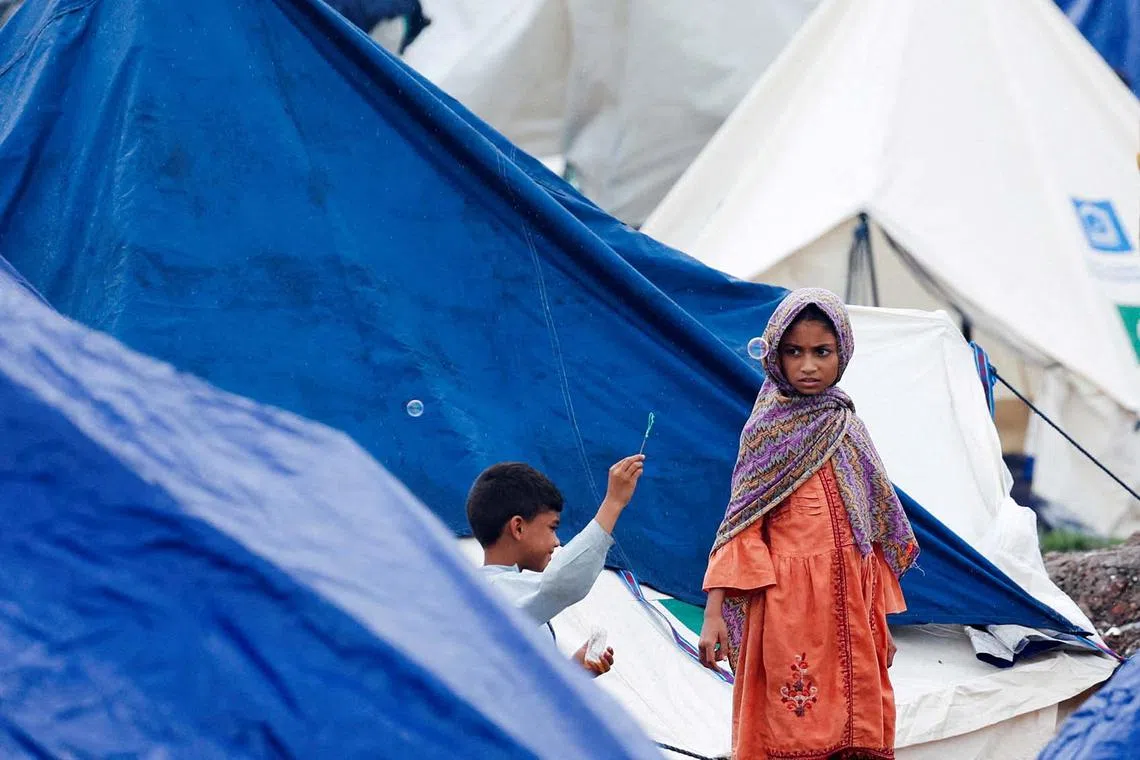 Children, who fled with their families from a flooded area, playing outside a tent, following recent floods caused by monsoon rains, in Lahore, Pakistan, Aug 31, 2025.