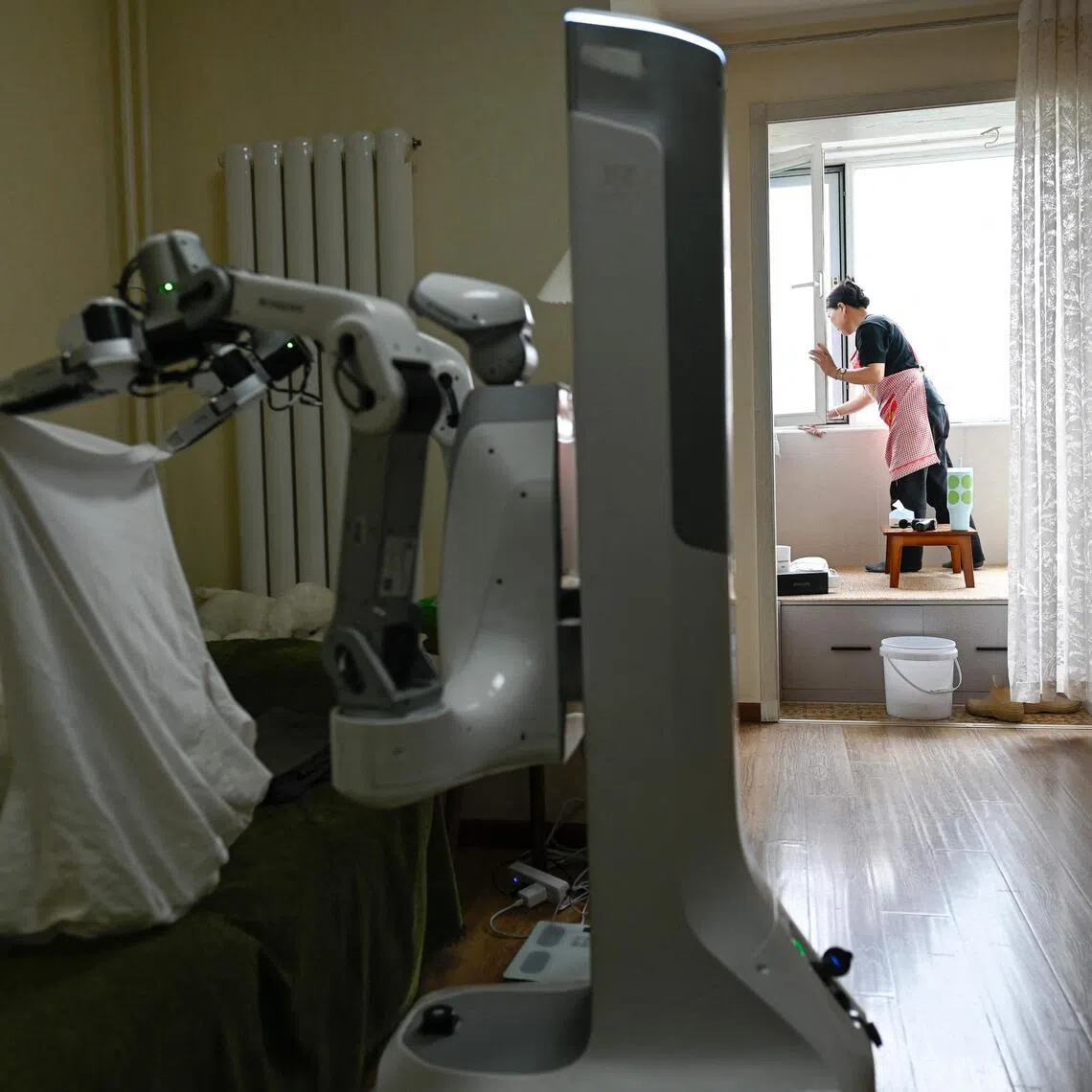 A housekeeper working alongside an X Square Robot at a customer's home in Beijing.