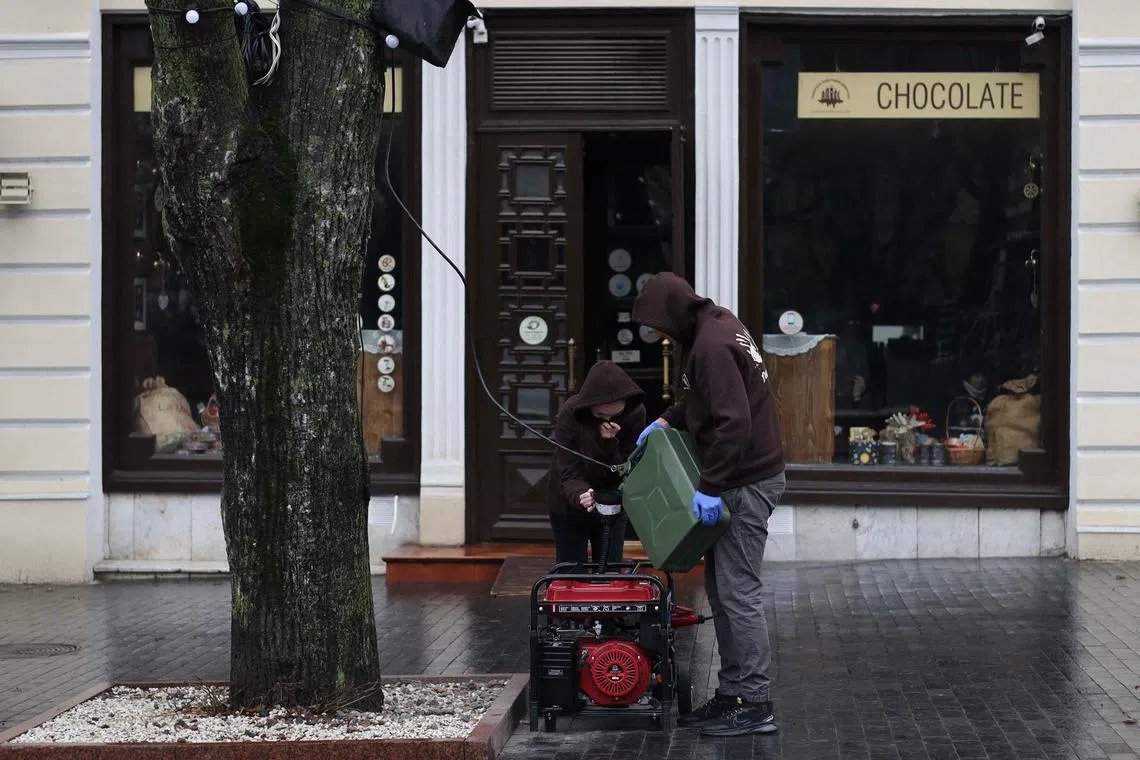 Employees of a chocolate workshop and cafe pour gasoline into a power generator in the Ukrainian city of Odesa, during a blackout, on Dec 16, 2022.