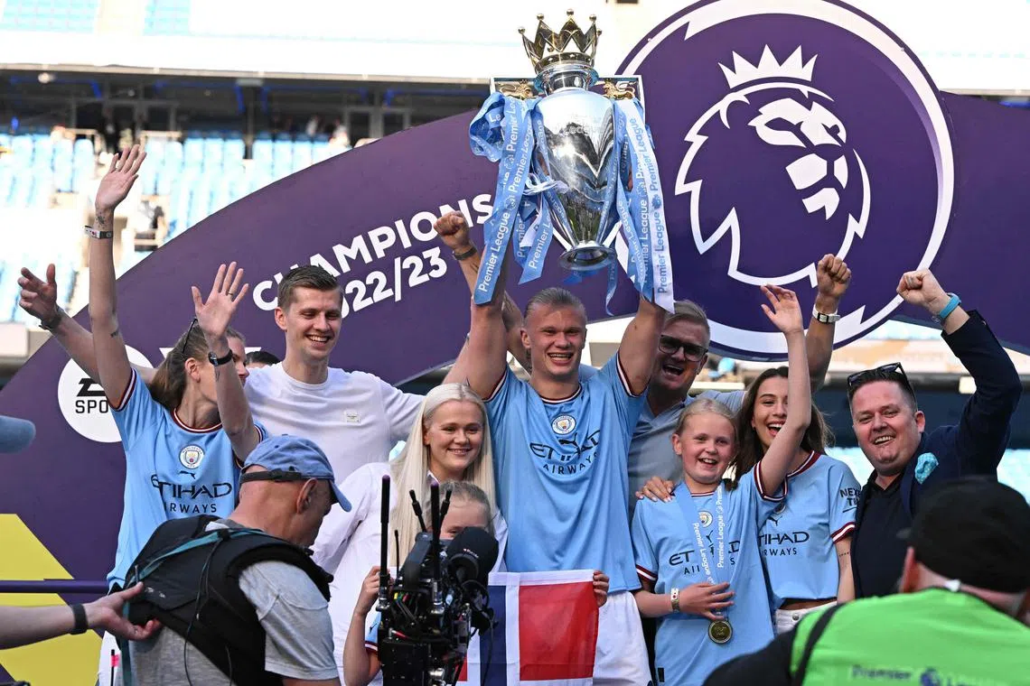 Manchester City's Erling Haaland lifting the Premier League trophy as he celebrates with his family after the presentation ceremony.
