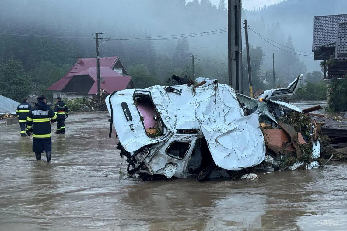 Emergency personnel work near a destroyed vehicle in a flooded area of the town of Brosteni in Suceava county, Romania, in this handout image released on July 28, 2025. Romanian General Inspectorate for Emergency Situations/Handout via REUTERS