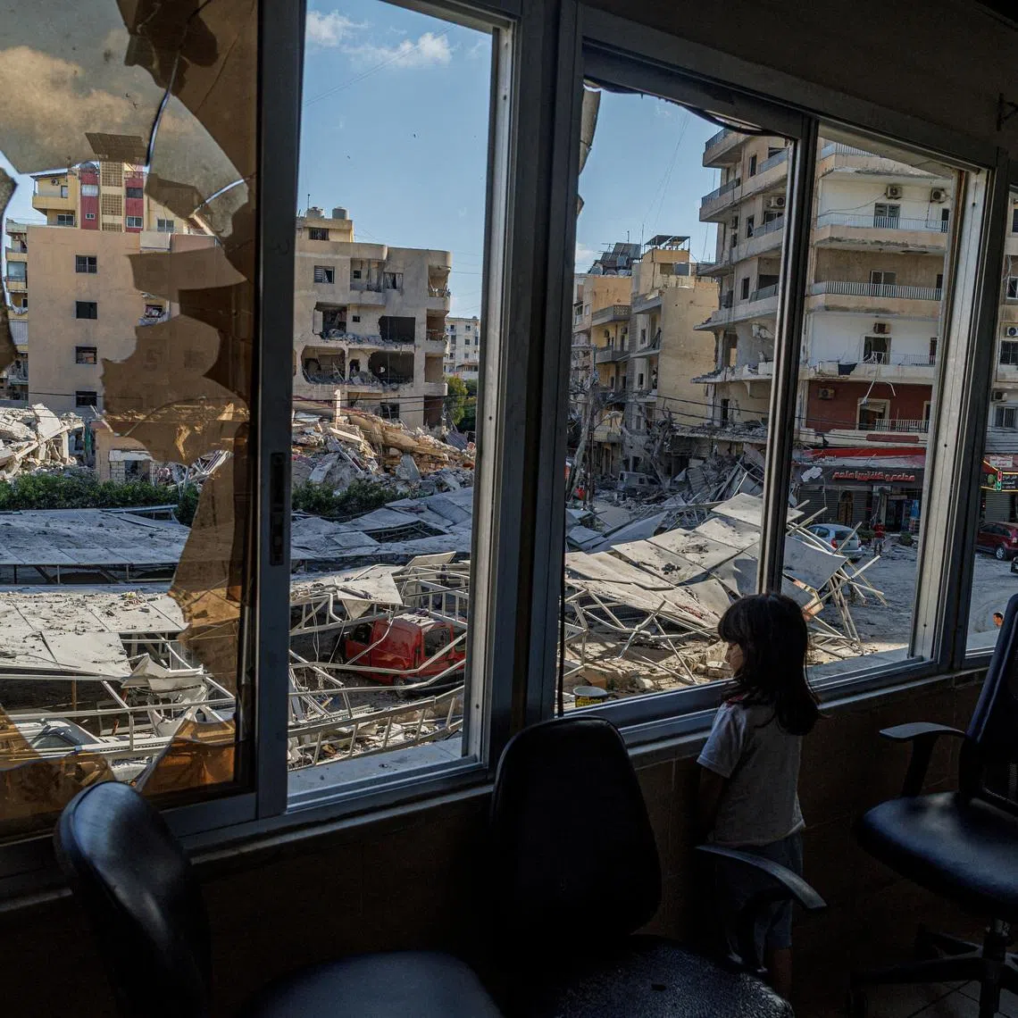 A displaced girl stands at the broken window of Jabal Amel hospital where she has taken shelter with her family, overlooking buildings damaged by Israeli strikes, following a deal between the U.S. and Iran, in Tyre, southern Lebanon, June 16, 2026. REUTERS/Zohra Bensemra