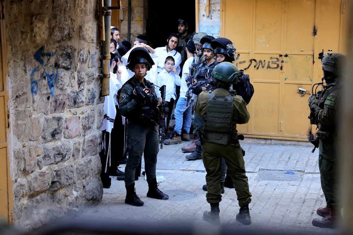 FILE PHOTO: Israeli troops stand guard during a weekly settlers' tour in Hebron, in the Israeli-occupied West Bank, August 30, 2025. REUTERS/Mussa Qawasma/File Photo
