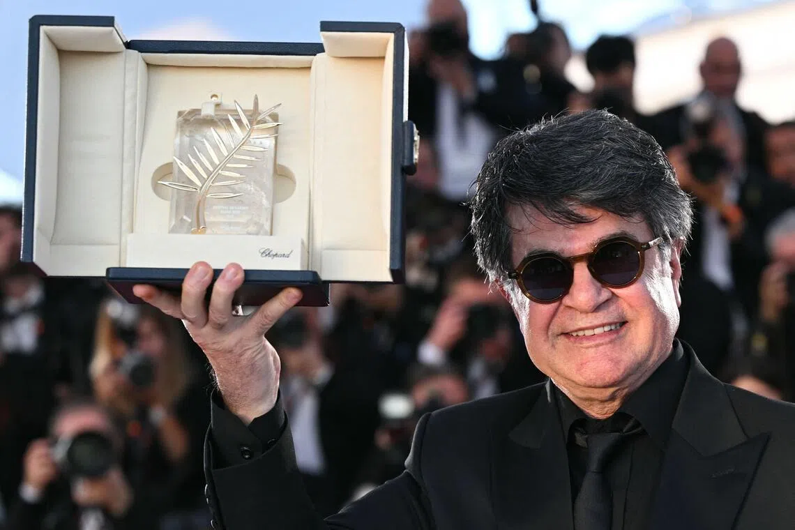 Iranian filmmaker Jafar Panahi shows off the trophy he received after winning the Palme d’Or at the Cannes film festival in 2025.