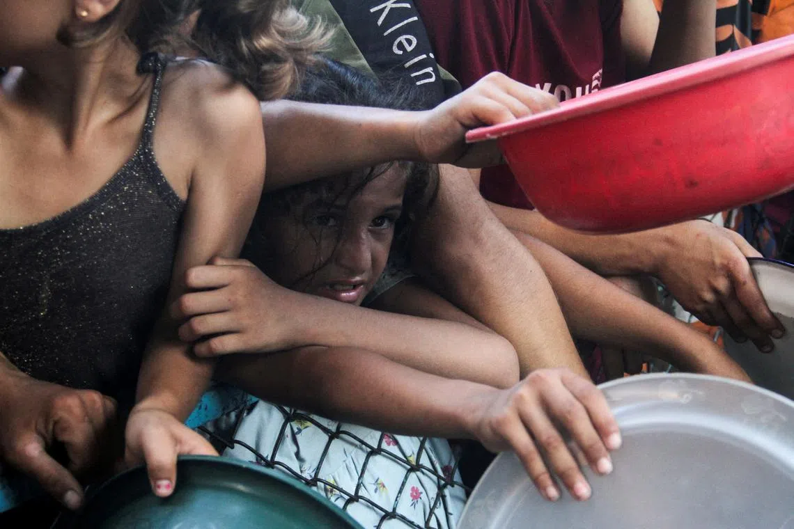 FILE PHOTO: A girl reacts, as she waits with other Palestinians to receive food cooked by a charity kitchen, amid a hunger crisis as conflict between Israel and Hamas continues, in the northern Gaza Strip August 14, 2024. REUTERS/Mahmoud Issa/File Photo