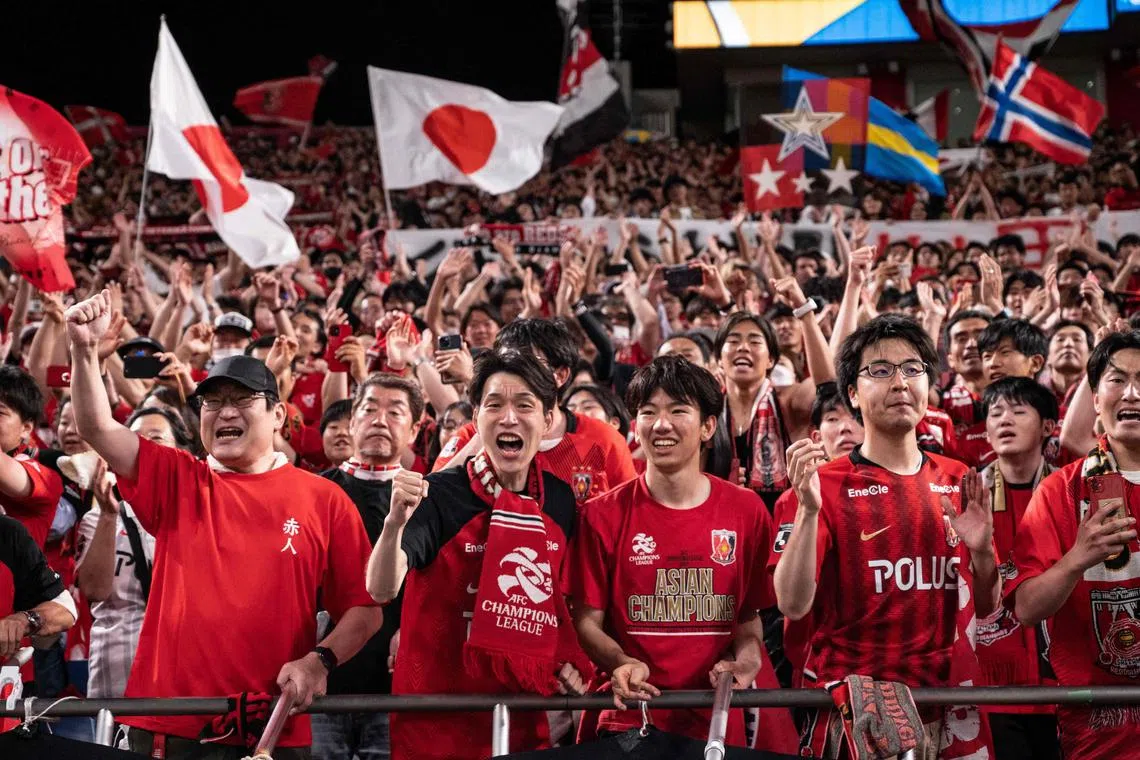 Urawa Red Diamonds fans celebrate in the stands after their team's victory against Al-Hilal in the second leg of the AFC Champions League final at Saitama Stadium.