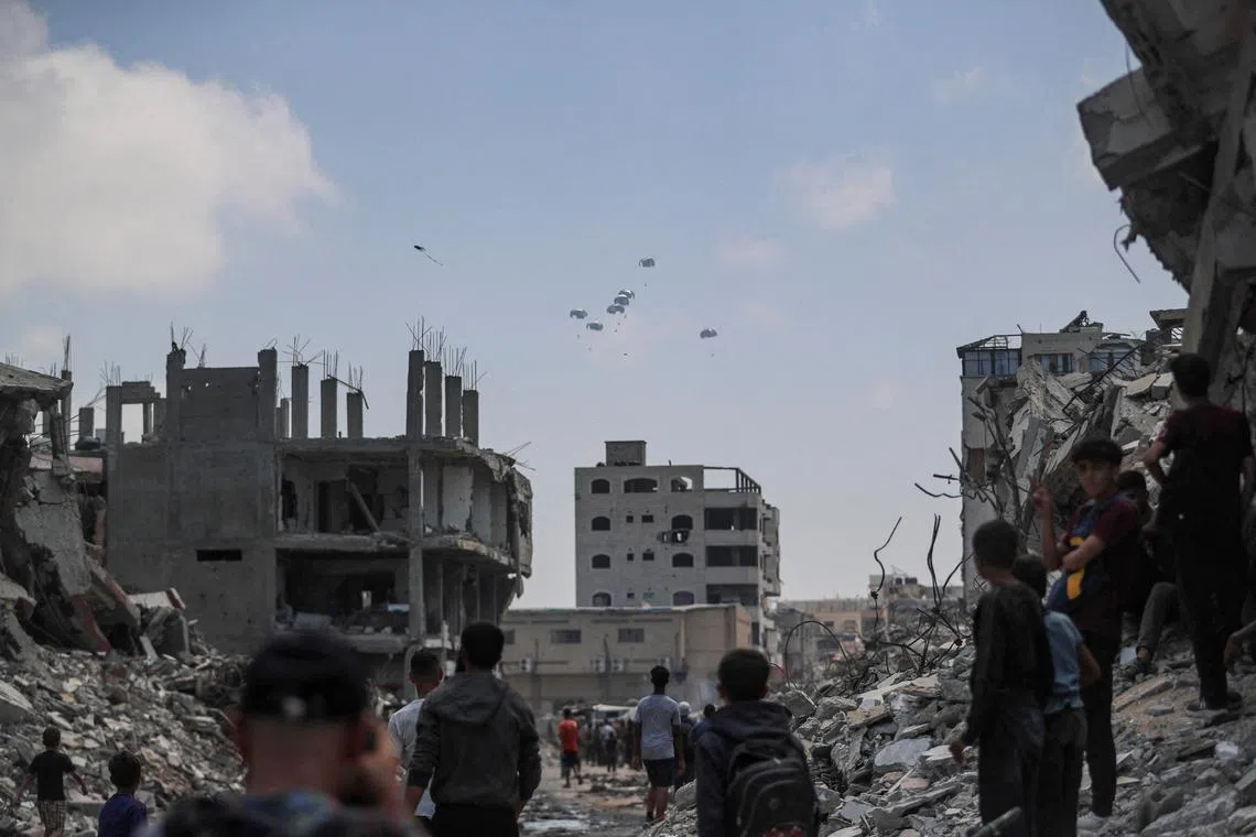 Palestinians look at aid packages that are airdropped over Gaza, in Gaza City, Aug 8, 2025.