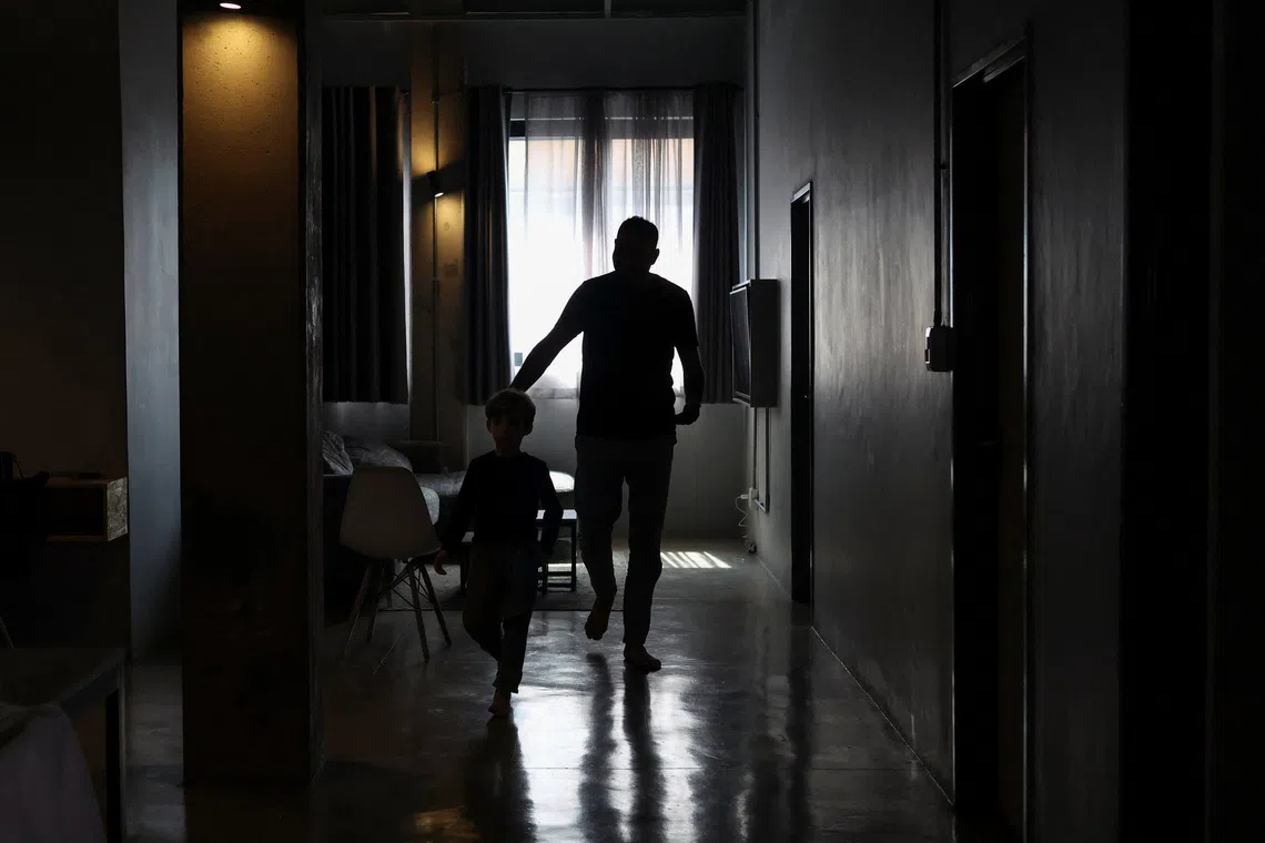 A Palestinian man, one of 130 granted entry to South Africa after initially being denied for not meeting immigration requirements, walks with his child after speaking to Reuters at an undisclosed location in Johannesburg, South Africa, November 14, 2025. REUTERS/Siphiwe Sibeko