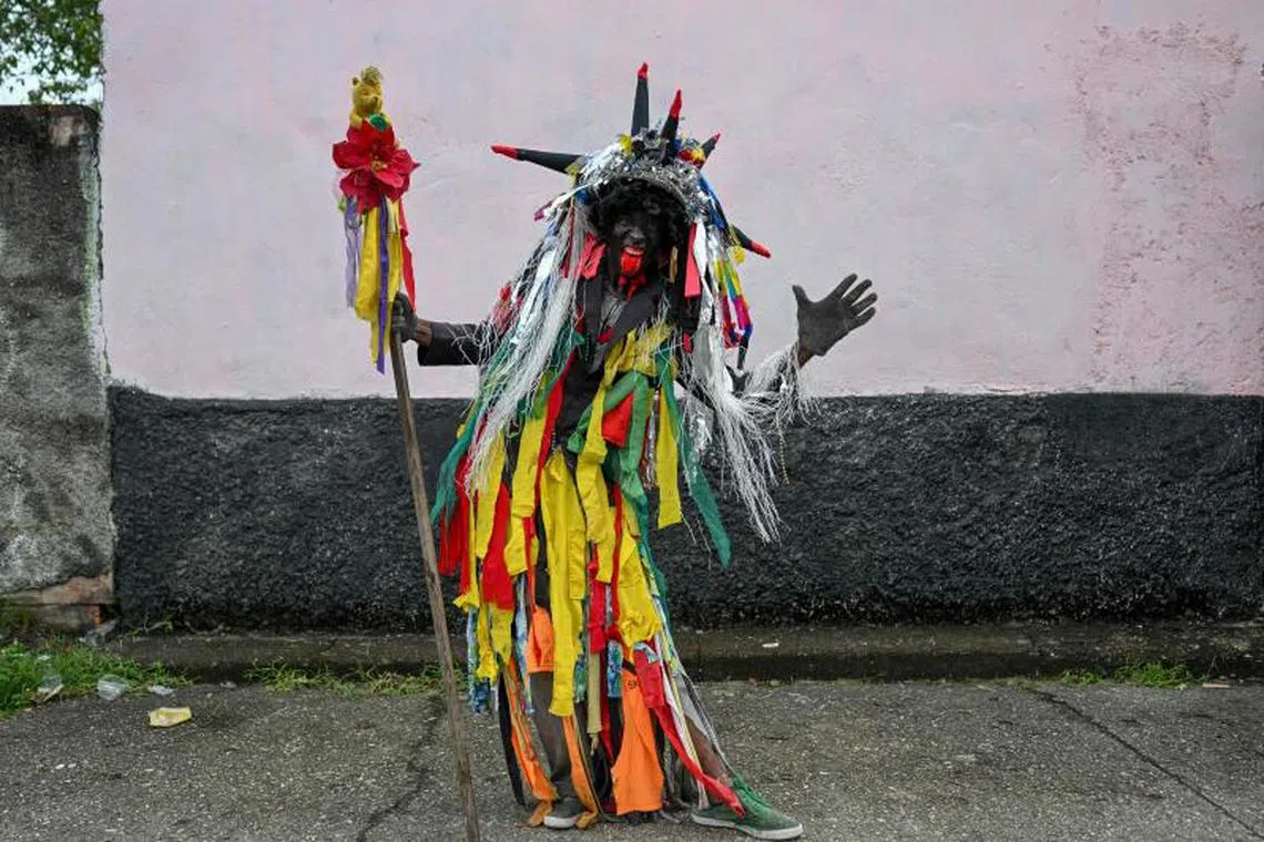 A man wearing old clothes and his face painted black stands for a portrait during the celebration of Holy Innocents Day in Caucagua, Miranda state, Venezuela, on December 28, 2022. PHOTO : AFP