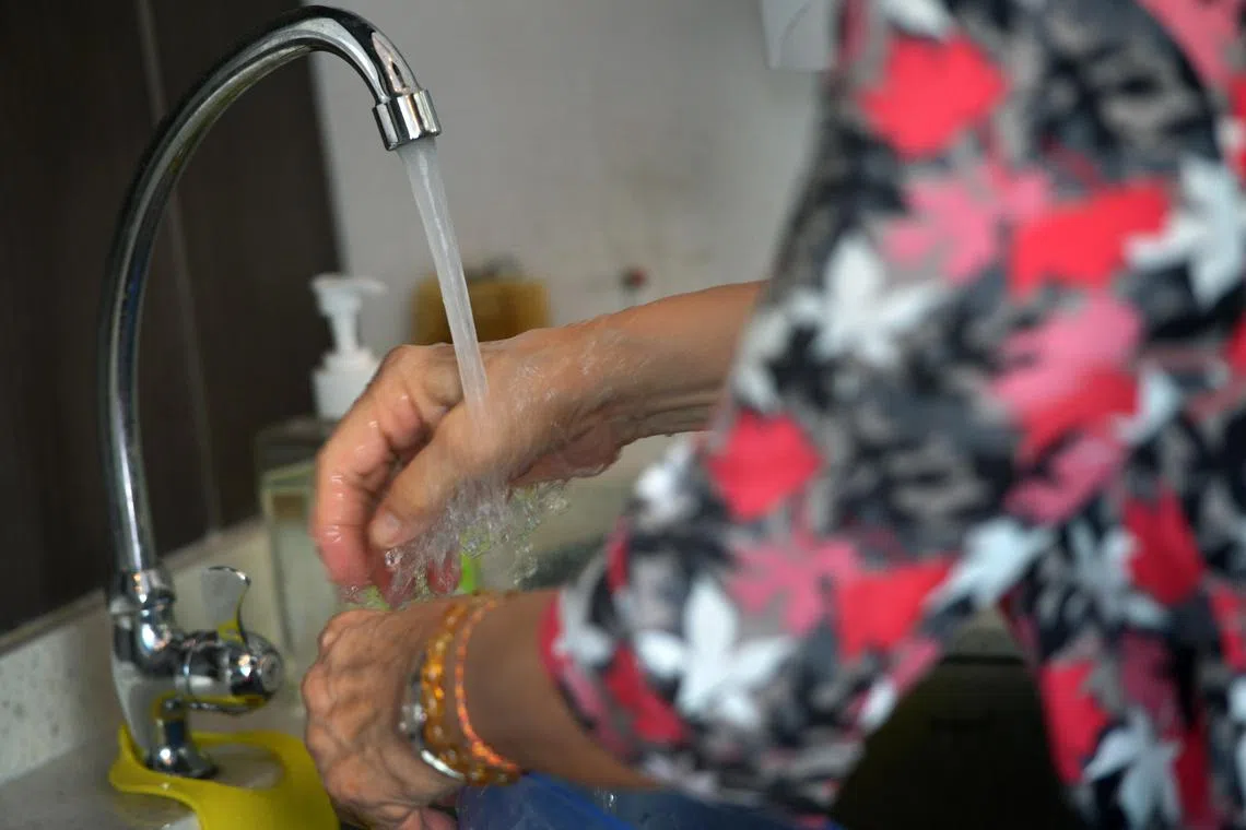 A woman washing her hands under a running tap at the sink at the Wellness centre located at the void deck of a block in Yishun Street 72.
